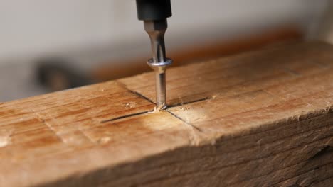 caucasian hand puts bolt in marked cross and screws in with cordless screwdriver