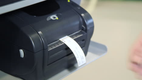 human hand taking printed label out of printer. printer for printing on tape