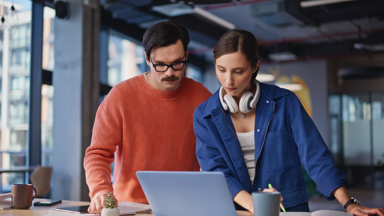 Membros da equipe ponderando soluções e olhando para um laptop em um espaço de trabalho em close-up