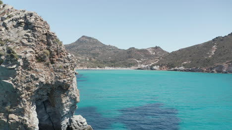 Toma-Lenta-Y-Reveladora-De-Una-Playa-Genérica-Con-Agua-Azul-Turquesa-Del-Océano-Y-Costa-De-Acantilados-Rocosos-En-Grecia