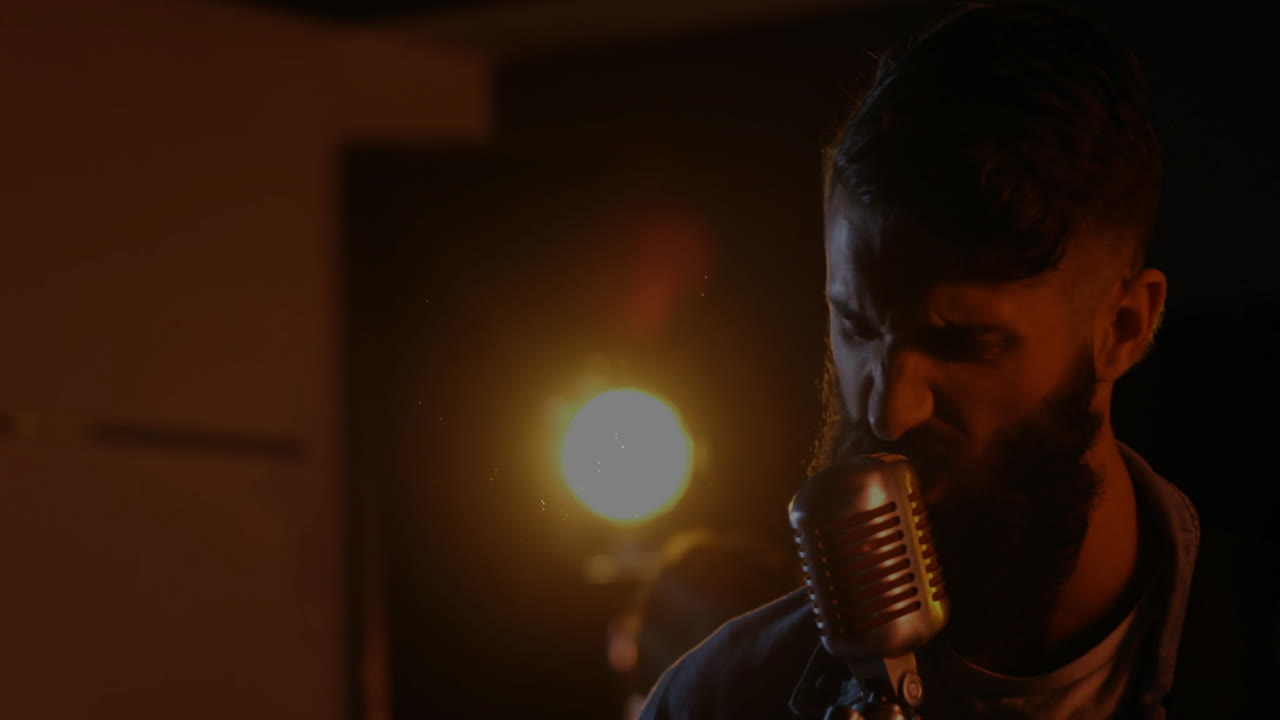 Male singer leaning into vintage mic in music studio, featuring light and animated spark effects