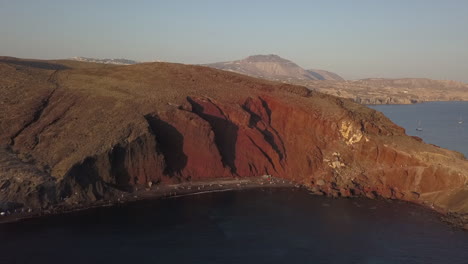 afternoon aerial view of iconic red beach cliffs on coast of santorini