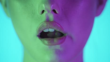 Extreme-close-up-shot-of-a-beautiful-plump-woman-lip-while-the-young-model-chews-a-delicious-and-sweet-gum-against-turquoise-background-in-slow-motion