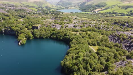 aerial view dorothea slate mining quarry woodland in snowdonia valley mountains with gorgeous shimmering blue lakes