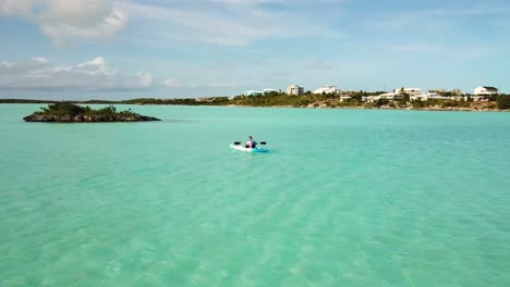 joven remando en un kayak en el océano frente a la costa de providenciales en el archipiélago de las islas turcas y caicos