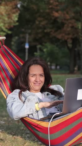 mujer trabajando en una computadora portátil en una hamaca