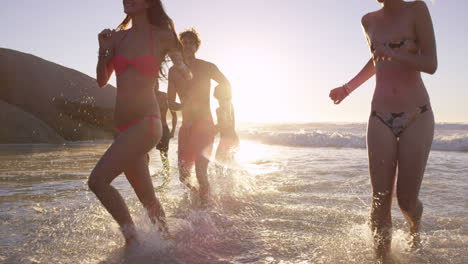 Diverse-Group-of-friends-swimming-in-the-sea-at-sunset