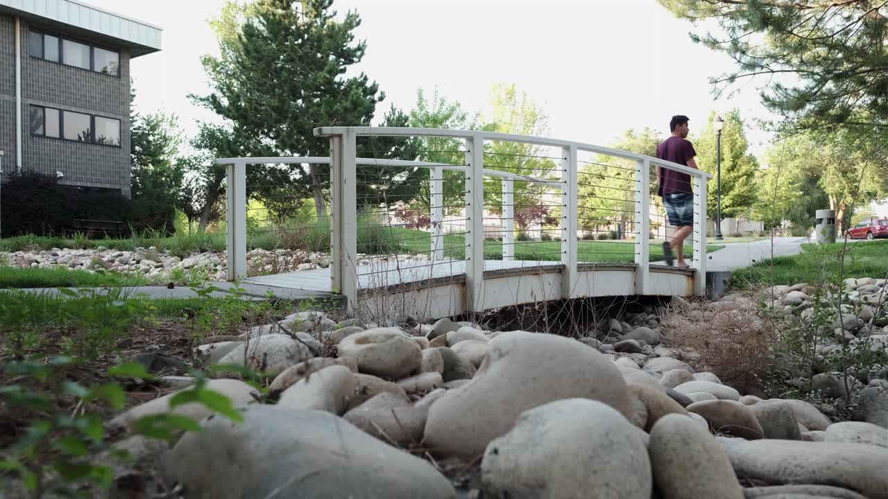 남자가 야외 공원,  ⁇ 은 날에 작은 보행 다리를 가로질러  ⁇ 습니다.