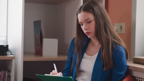 businesswoman marks notes on clipboard in office. thoughtful woman in formal clothes checks tasks in to do list at workplace. corporate lifestyle