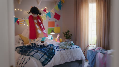 happy little girl jumping on bed wearing costume playing game enjoying playful imagination in colorful bedroom at home