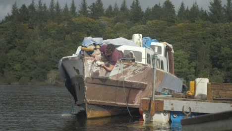 Un-Joven-Arreglando-Un-Clásico-Crucero-A-Motor-Limpiando-La-Proa-Carenada