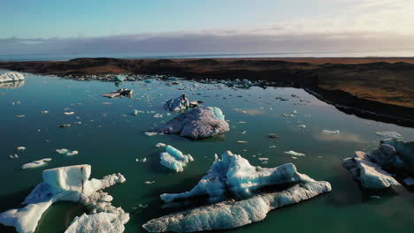 Flying-Over-The-Icebergs-Of-The-Jokusarlon-Glacial-Lake-In-South-East-Iceland-On-A-Clear-Sunny-Day---Aerial-Shot