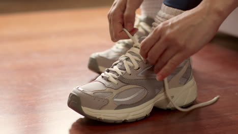 close up of woman at home lacing up training shoes before exercising