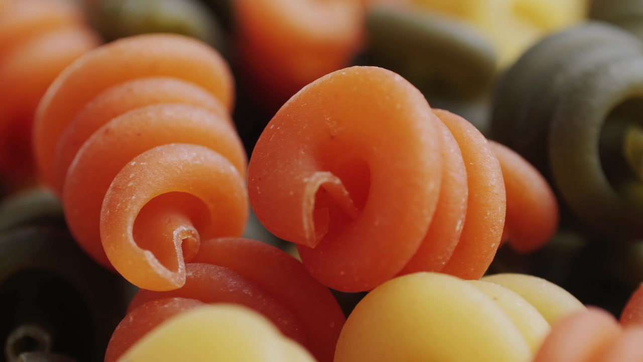 Nærbillede af farverig ukogt spiralpasta der roterer langsomt