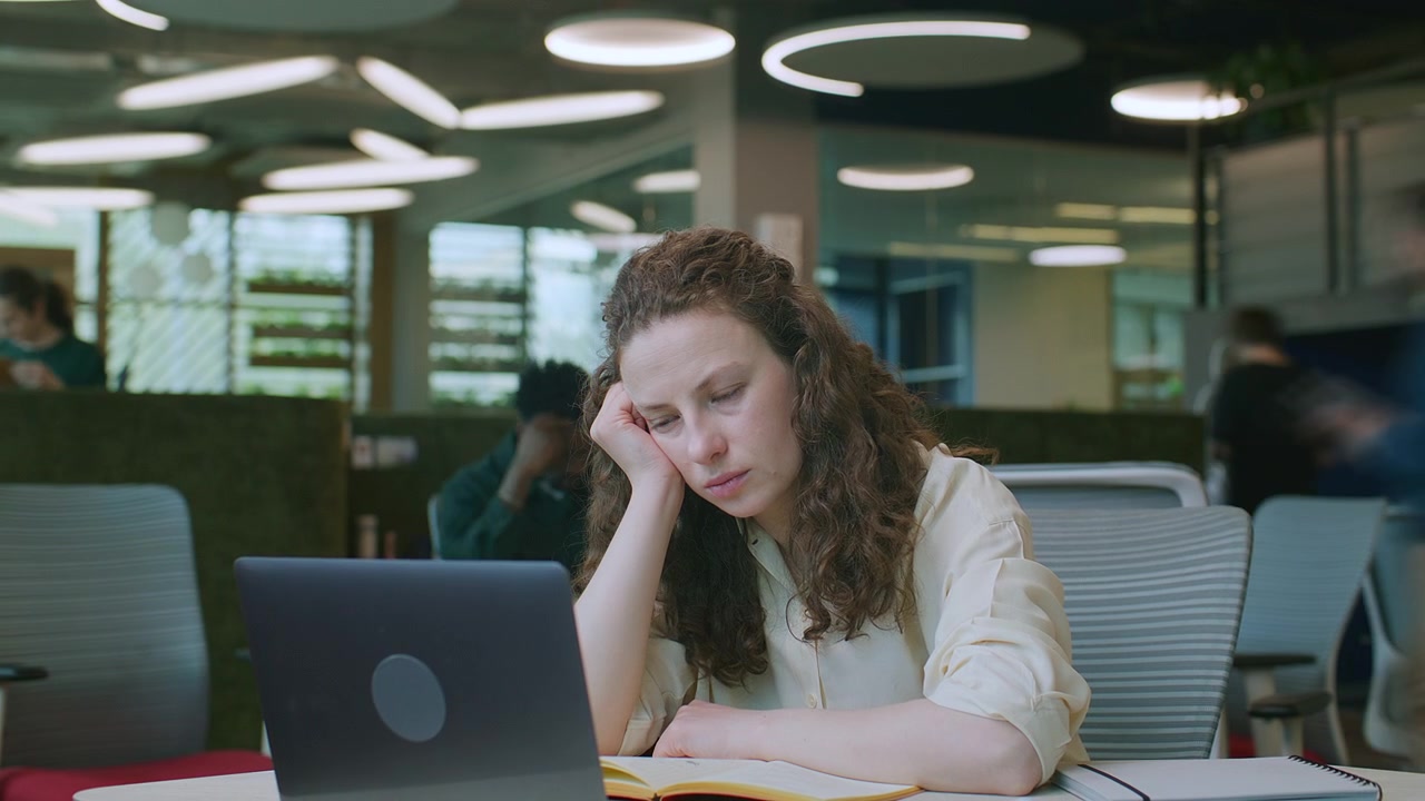 Timelapse di una donna d'affari stanca che fissa il computer portatile in ufficio