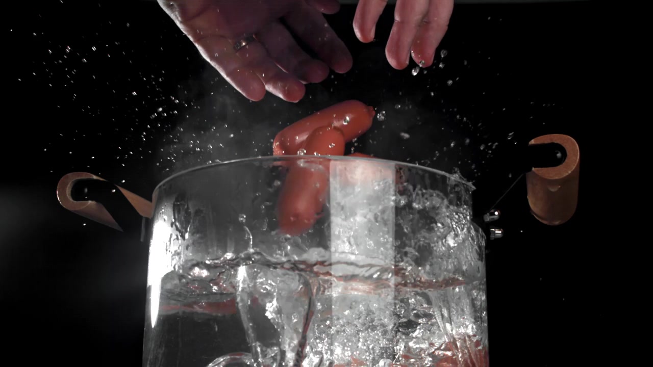 Salsicce che cadono nell'acqua bollente al rallentatore