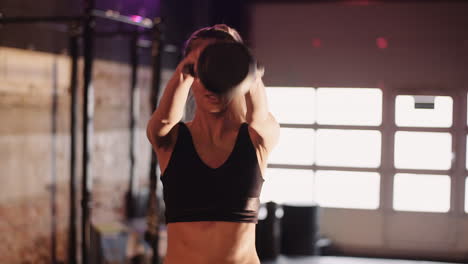 Confident-Young-Woman-Exercising-With-Kettlebell-During-Training-At-Gym