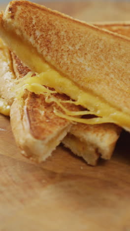 video de primer plano de un sándwich de pan blanco con queso recién preparado en una tabla de madera