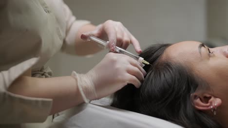 a patient undergoes mesotherapy, receiving targeted injections from a healthcare professional into the scalp to promote hair health