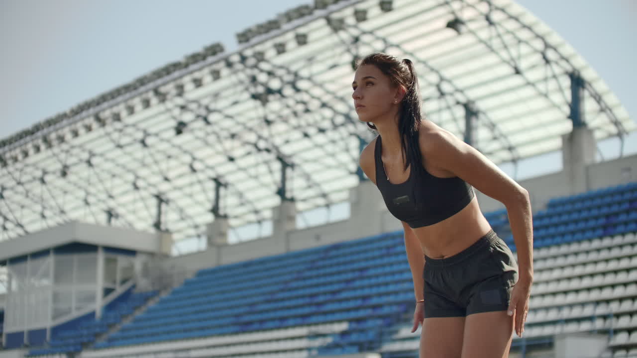 cámara lenta: atleta mujer esperando en el bloque de salida en la pista de carrera