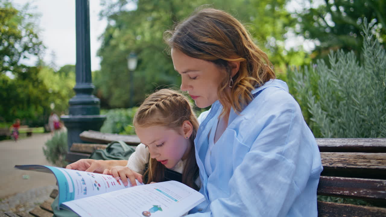Closeup family learning park. Attentive mother small daughter doing homework