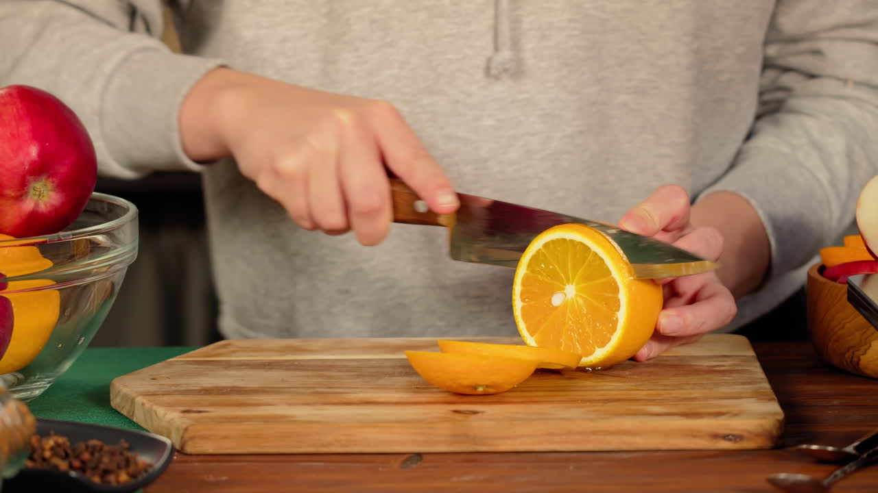 Mãos Fatiando Laranja Fresca em uma Tábua de Corte de Madeira