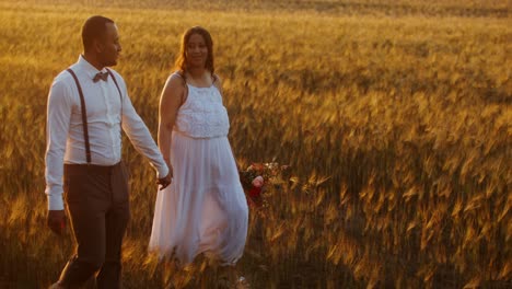 pareja caminando de la mano en un campo de trigo al atardecer