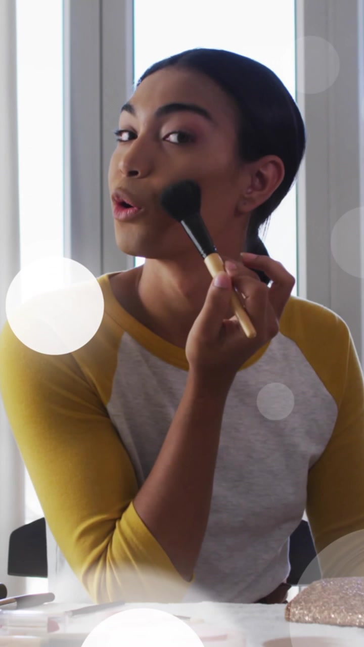 Animation of light spots over woman applying make-up