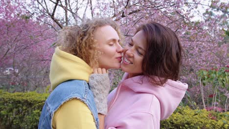 lesbian couple kissing under cherry blossoms