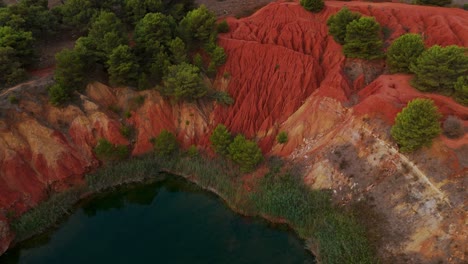 otranto, puglia, italy - a sweeping view of the bauxite cave with its lake encircled by vibrant, lush greenery - aerial drone shot