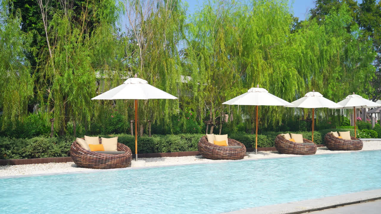 바다를 배경으로 수영장 주변에 침대 수영장이 있는 우산 - 휴일 및 휴가 개념