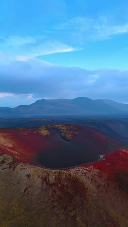 approaching the sleeping volcano crater with red soil. misty view of mountain range at backdrop. iceland panorama. vertical video.