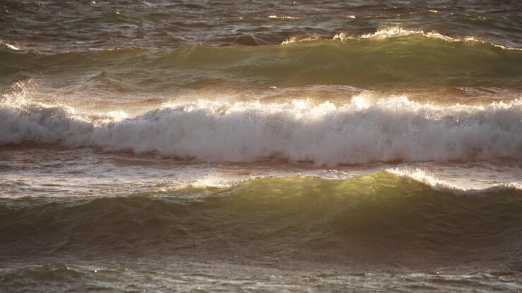 Inquadratura statica di onde che si infrangono con un caldo bagliore del sole al tramonto, in slow motion