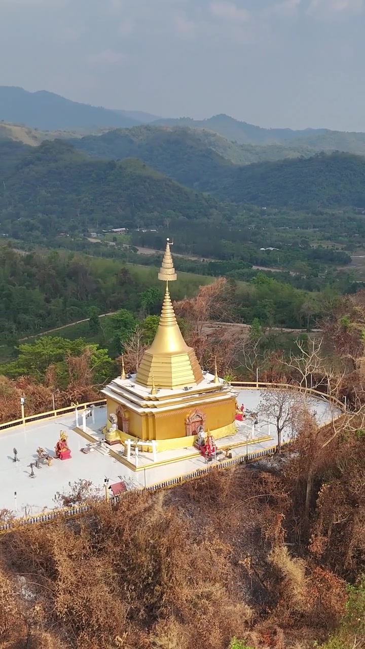 Orbita aerea verticale attorno alla pagoda dorata, sacro stupa buddista su una cima di montagna rurale, presso il tempio Wat Pa Sawang Bun, Saraburi, Thailandia.