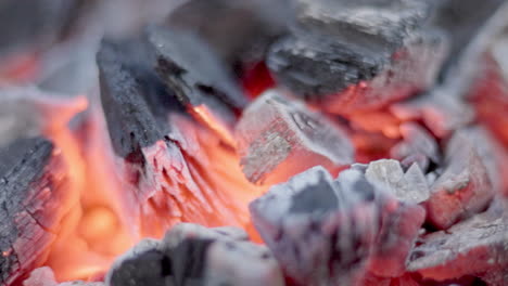 a tight shot of red-hot charcoal glowing intensely on a grill, capturing the raw heat and texture of the fire in action.