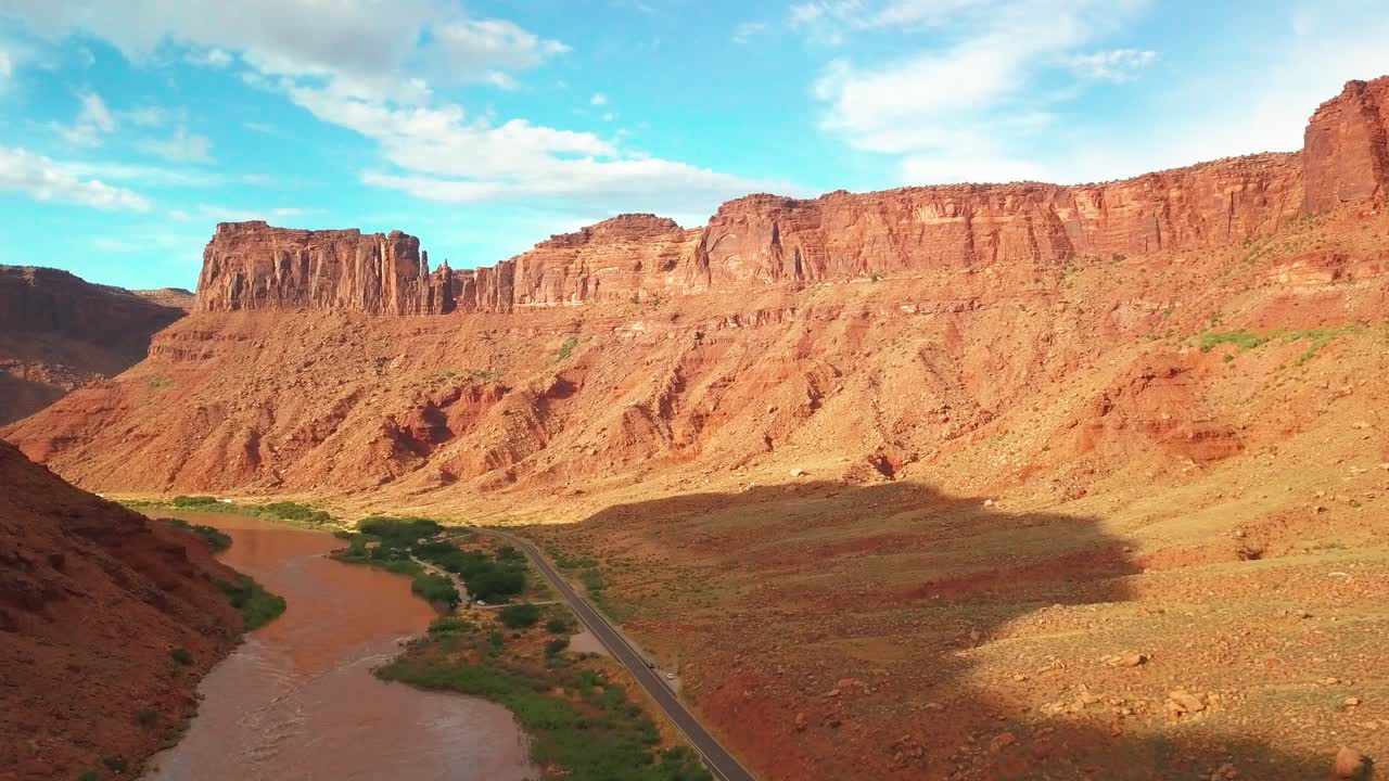 vuelo de descenso aéreo sobre una carretera panorámica a lo largo del río colorado con altas paredes del cañón por encima