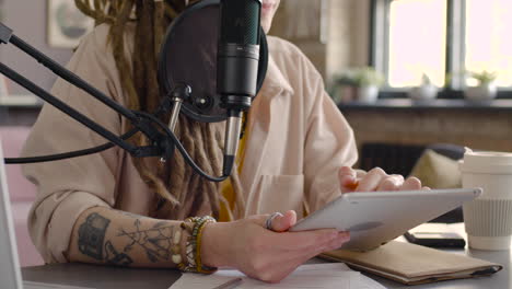 Close-Up-View-Of-Woman-Hands-Holding-And-Tapping-On-A-Tablet-While-Recording-A-Podcast-Talking-Into-A-Microphone-1