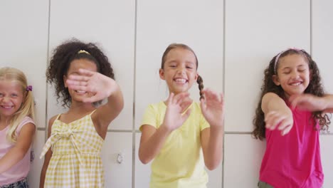 Video-of-happy-diverse-girls-waving-at-camera-at-school-corridor