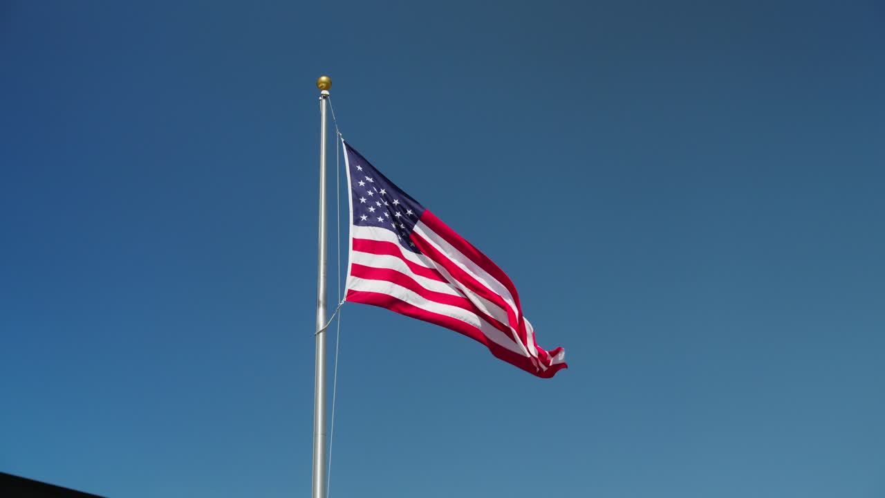 bandera estadounidense ondeando contra el cielo azul