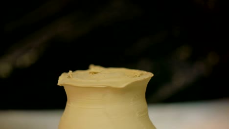 professional potter carving mug with special tool in pottery workshop