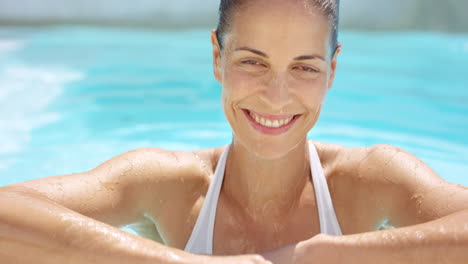 Mujer-Atractiva-Nadando-Hasta-El-Borde-De-La-Superficie-De-La-Piscina-Y-Sonriendo