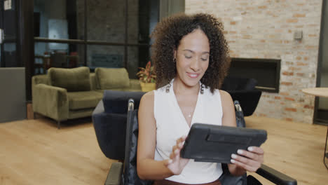 Retrato-De-Una-Empresaria-Birracial-En-Silla-De-Ruedas-Usando-Una-Tableta-En-La-Oficina-Y-Sonriendo,-En-Cámara-Lenta