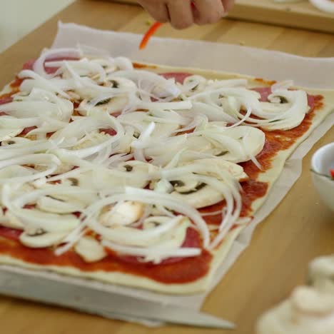 Mujer-Colocando-Cebolla-En-Una-Pizza-Casera