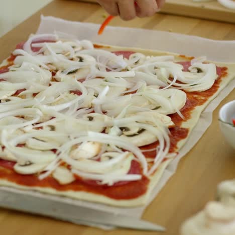 mujer colocando cebolla en una pizza casera