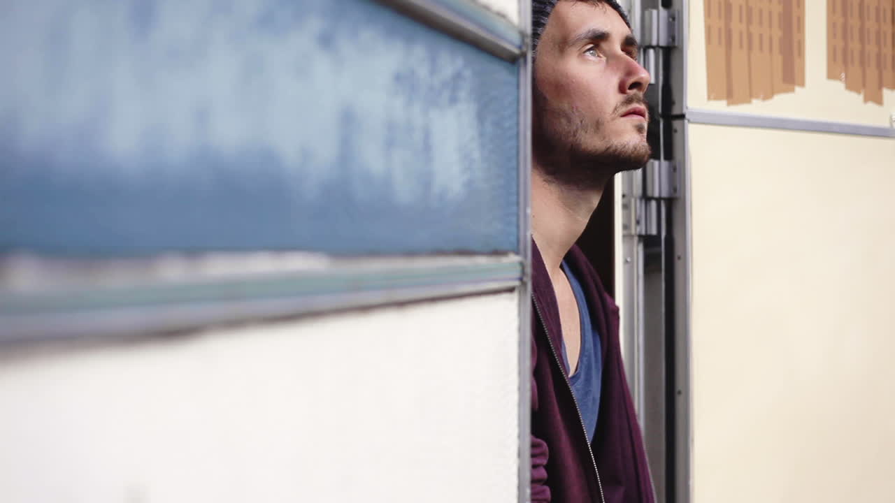 Primo piano di un uomo in cerca di ispirazione per scrivere, seduto in un furgone con la porta aperta