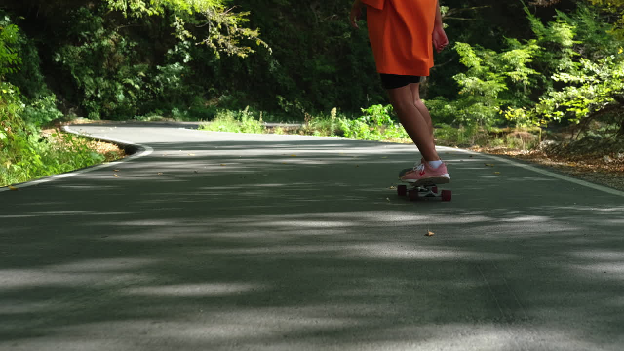 숲 속 의 휘어지는 도로 에서 스케이트보드 를 타고 있는 사람