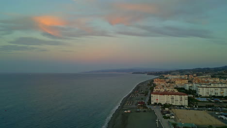 Una-Vista-De-Una-Ciudad-En-La-Costa-Con-El-Agua-Del-Mar-Formando-Suaves-Olas-En-España.