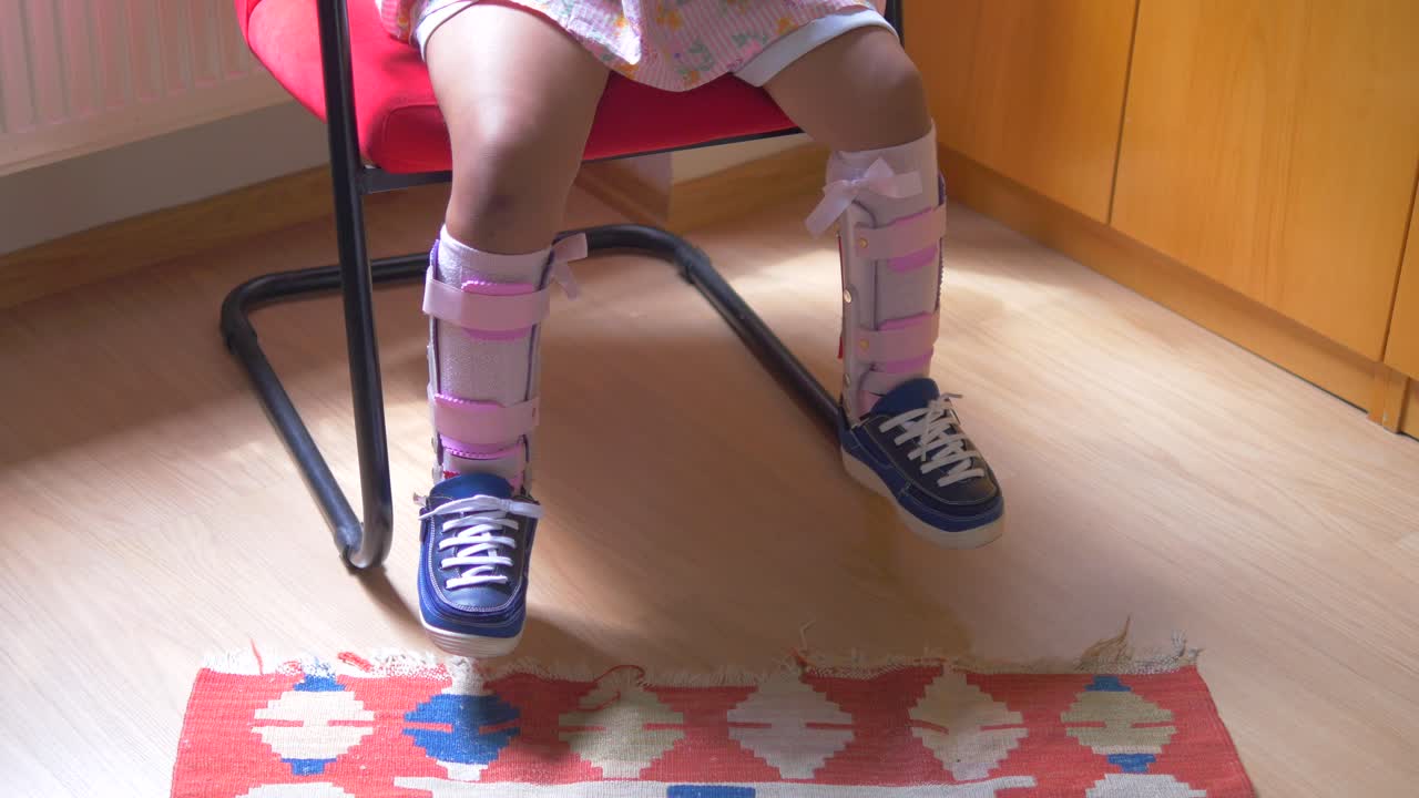 의자 에 앉아 있는 다리 브레이스 를 가진 아이