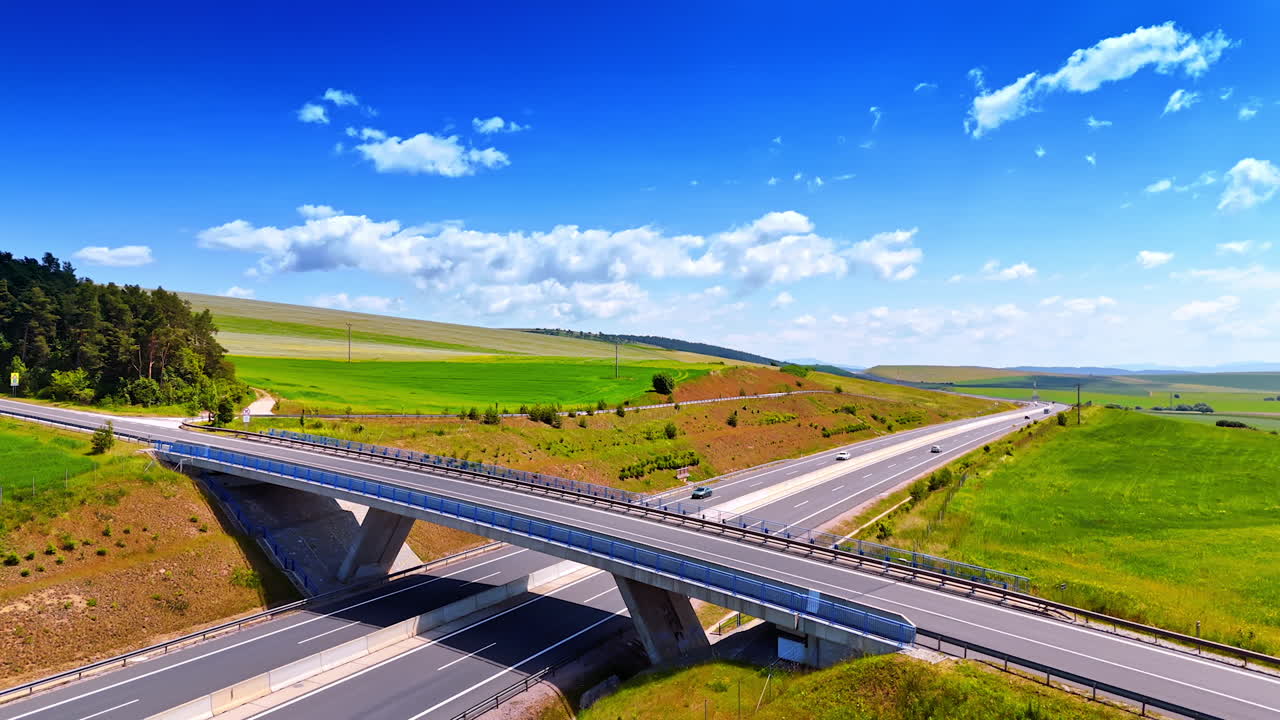 Approaching the bridge with road over the highways. Vast fields are around the roads.