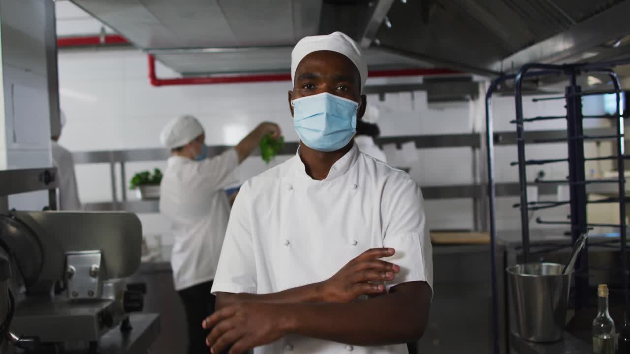 Portrait of african american male chef wearing face mask with arms crossed